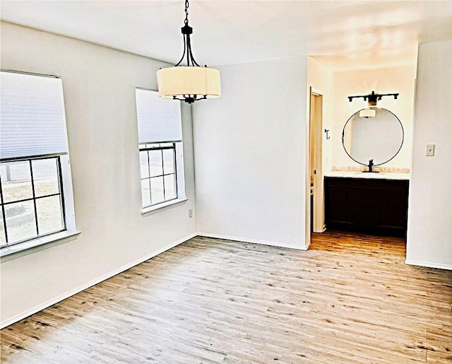 spare room with a sink, wood finished floors, and baseboards