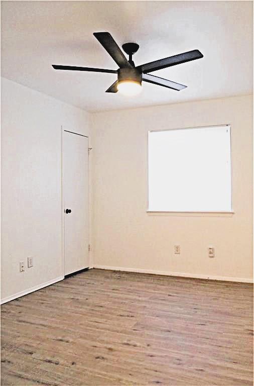 spare room featuring ceiling fan, baseboards, and wood finished floors