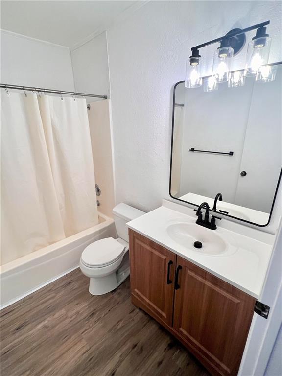 full bath with shower / tub combo, vanity, toilet, and wood finished floors