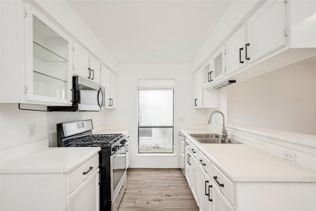 kitchen featuring white cabinetry, light countertops, light wood-type flooring, stainless steel appliances, and a sink