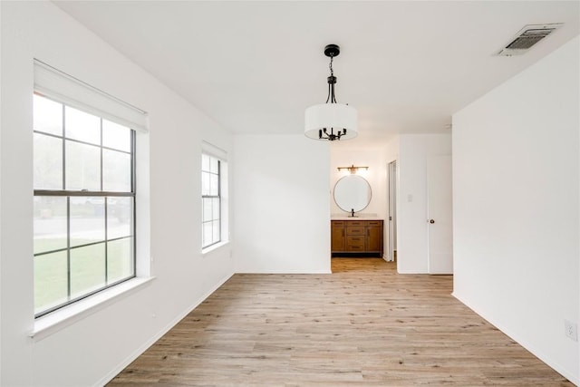 unfurnished dining area featuring light wood-type flooring and visible vents