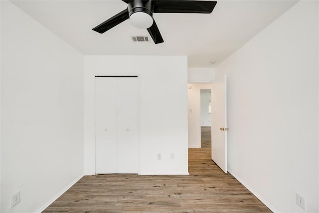 unfurnished bedroom with baseboards, visible vents, a ceiling fan, a closet, and wood finished floors