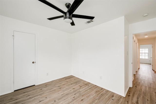 empty room with light wood finished floors, visible vents, and a ceiling fan