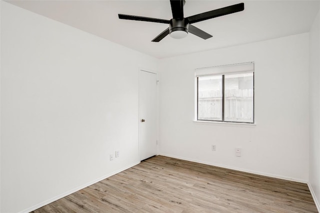spare room featuring baseboards, light wood-style floors, and a ceiling fan