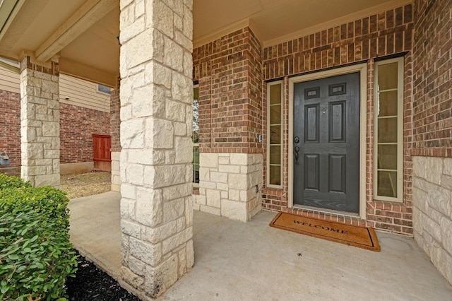 property entrance featuring stone siding, a porch, and brick siding