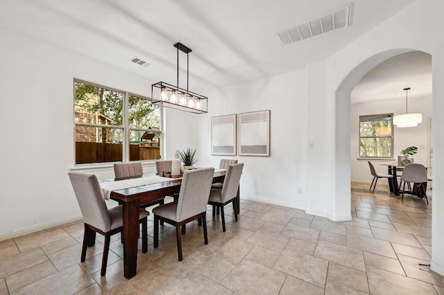 dining room with arched walkways, visible vents, and baseboards