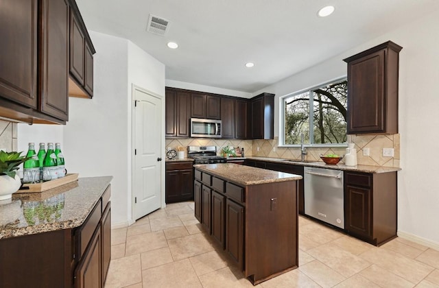 kitchen with dark brown cabinetry, visible vents, appliances with stainless steel finishes, and stone counters