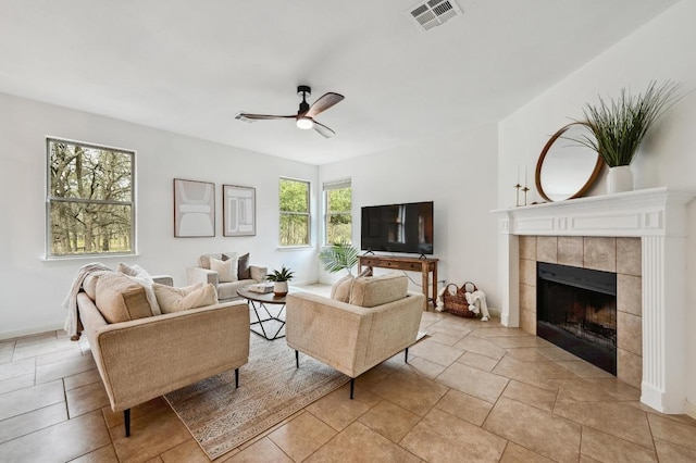 living room with a ceiling fan, baseboards, visible vents, and a tiled fireplace