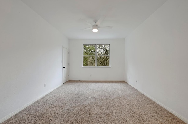 empty room with light carpet, a ceiling fan, and baseboards