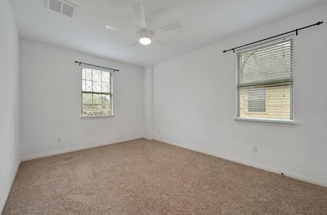 carpeted spare room with a ceiling fan, visible vents, and baseboards