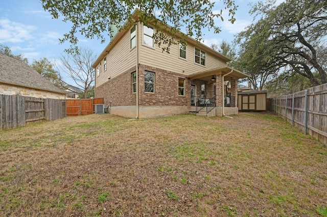 back of property with a storage shed, a lawn, a fenced backyard, an outbuilding, and brick siding