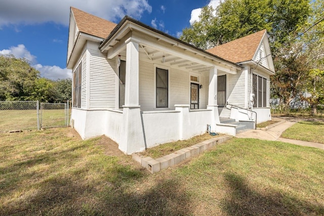 view of home's exterior with a yard, a shingled roof, covered porch, a gate, and fence