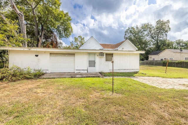 view of front of home with a front yard, a wall mounted air conditioner, fence, and an attached garage