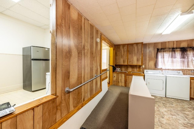 washroom with independent washer and dryer, laundry area, wood walls, and a sink