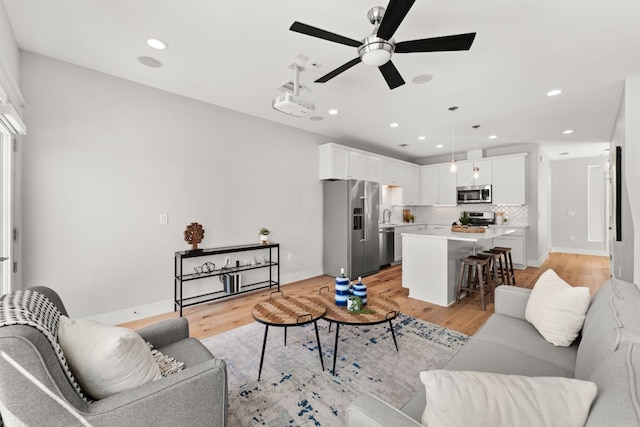 living area featuring light wood-type flooring, a ceiling fan, and recessed lighting