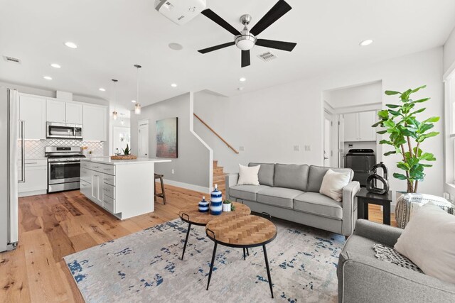 living room with stairway, visible vents, and light wood-style flooring