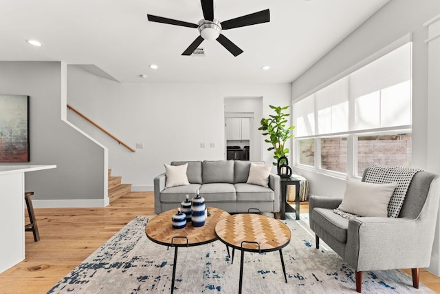 living room with baseboards, visible vents, light wood-style flooring, stairs, and recessed lighting