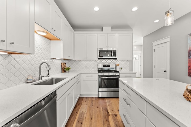 kitchen with appliances with stainless steel finishes, white cabinets, and a sink