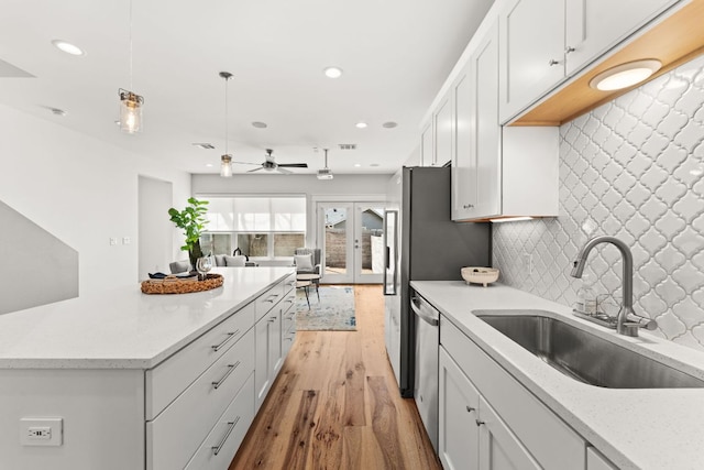 kitchen with tasteful backsplash, white cabinetry, a sink, and light wood finished floors