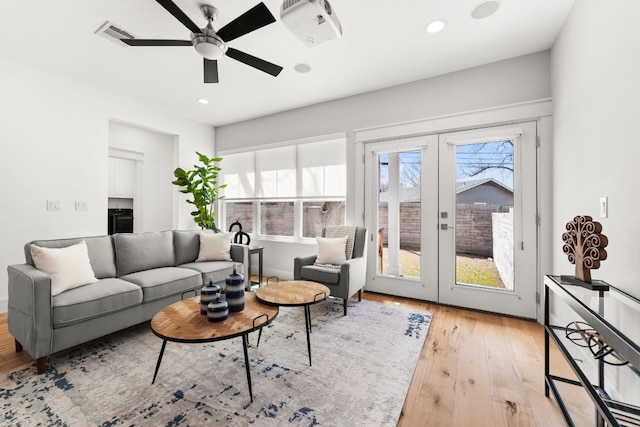 living room featuring recessed lighting, french doors, a healthy amount of sunlight, and hardwood / wood-style flooring