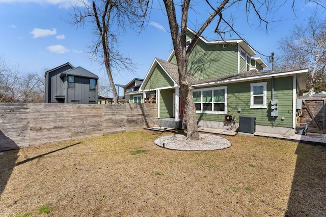 back of property featuring central air condition unit, fence, and a yard