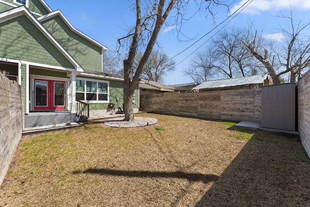 view of yard with french doors, a shed, an outdoor structure, and fence