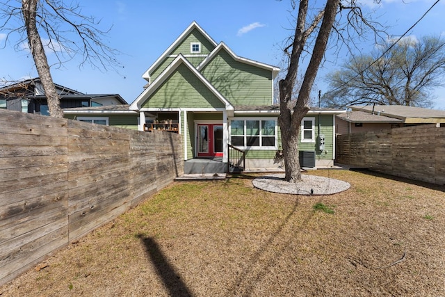 view of front of home with a front yard, a fenced backyard, and cooling unit