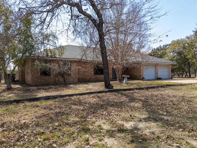 ranch-style home featuring concrete driveway, brick siding, roof with shingles, and an attached garage