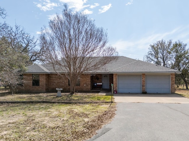 ranch-style house with a shingled roof, concrete driveway, brick siding, and an attached garage