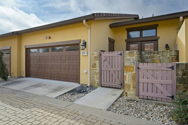 102 Gallia Dr Unit 3, Austin, TX 78734 - view of front facade with a gate, a garage, stucco siding, and driveway