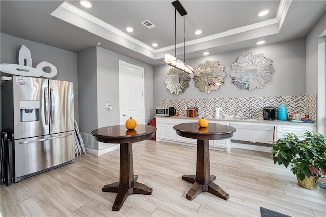 interior space with visible vents, a raised ceiling, light wood-style flooring, crown molding, and recessed lighting