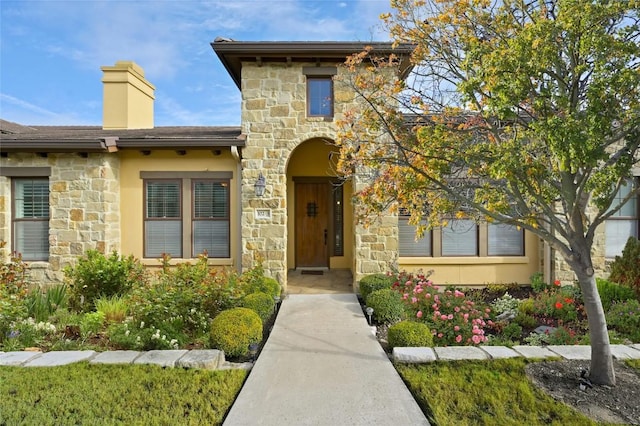 doorway to property featuring a chimney and stucco siding