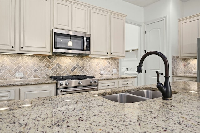 kitchen featuring light stone countertops, backsplash, stainless steel appliances, and a sink