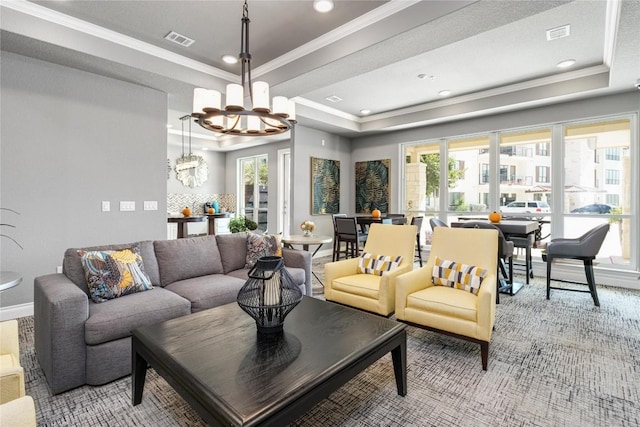 living room featuring ornamental molding, a tray ceiling, visible vents, and an inviting chandelier