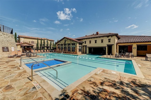 community pool featuring a hot tub, fence, and a patio