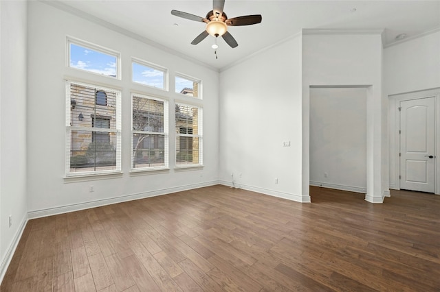 unfurnished room featuring a healthy amount of sunlight, crown molding, baseboards, and dark wood-style flooring