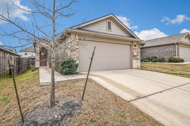 view of side of home featuring a garage, driveway, brick siding, and fence