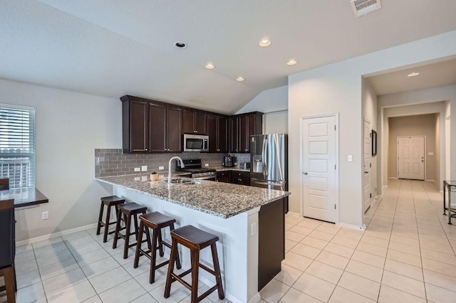 kitchen featuring light tile patterned floors, stainless steel appliances, visible vents, dark brown cabinets, and light stone countertops