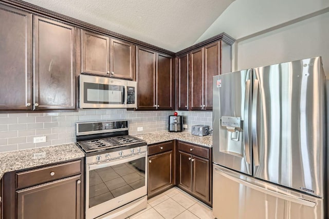 281 Gaida Loop, Georgetown, TX 78628 - kitchen featuring stainless steel appliances, dark brown cabinets, decorative backsplash, light tile patterned floors, and lofted ceiling