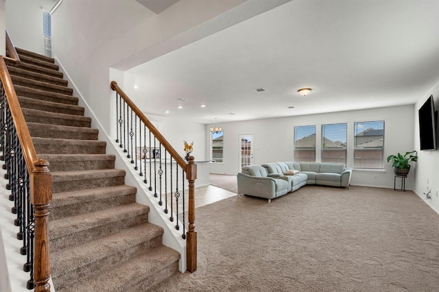 carpeted living room with visible vents, baseboards, stairway, a chandelier, and recessed lighting