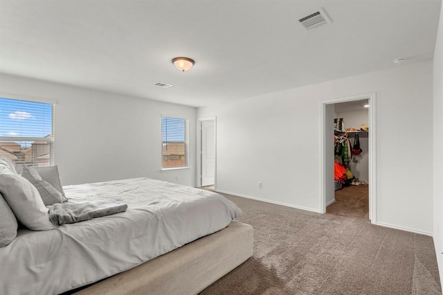 bedroom featuring carpet floors, visible vents, a spacious closet, and baseboards