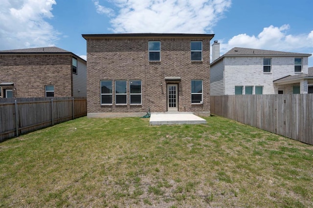 back of house featuring a yard, a fenced backyard, and brick siding