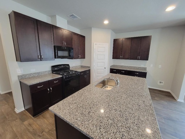 kitchen featuring black appliances, wood finished floors, a sink, and visible vents