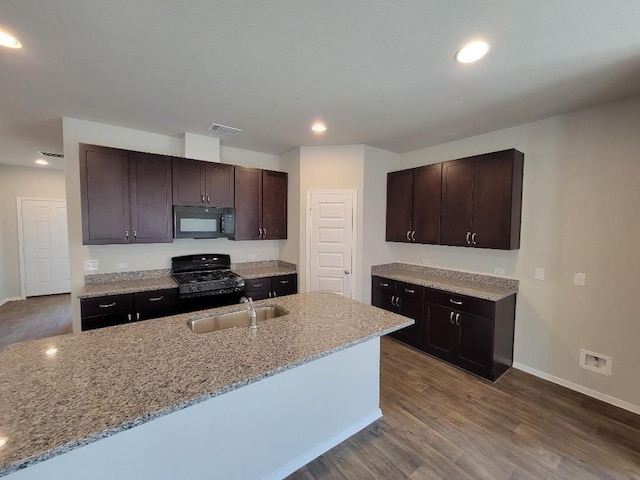 kitchen with dark brown cabinetry, visible vents, dark wood-style floors, black appliances, and a sink