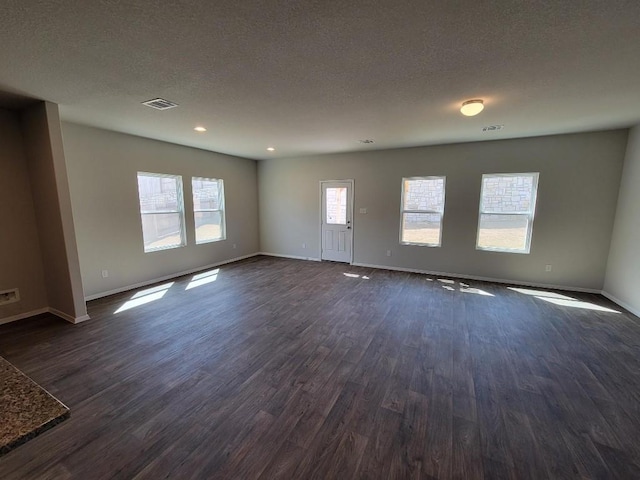 unfurnished living room featuring visible vents, dark wood finished floors, a textured ceiling, and baseboards