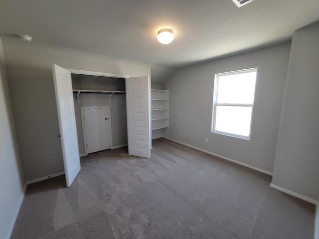 unfurnished bedroom with carpet, a closet, vaulted ceiling, and baseboards