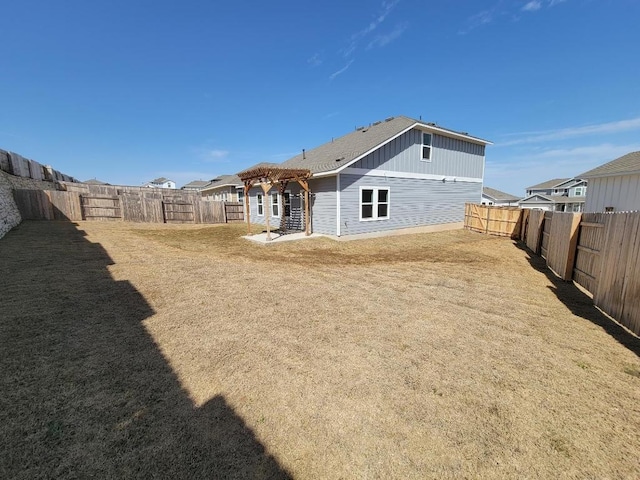 rear view of property with a fenced backyard, a pergola, and a yard