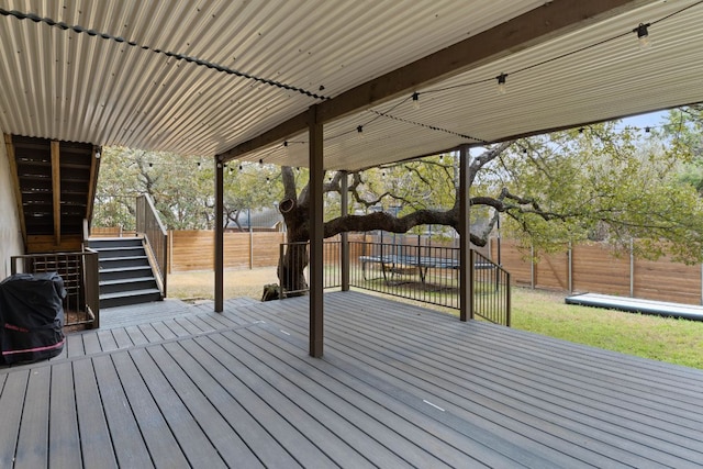 wooden deck with a trampoline, a fenced backyard, and stairs