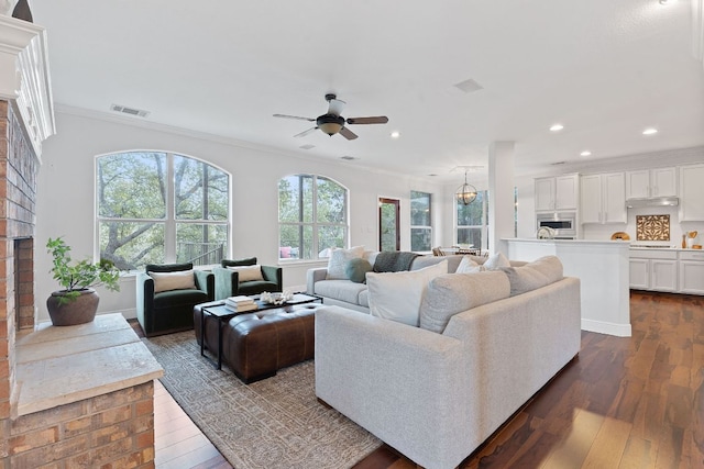 living room with dark wood-style floors, recessed lighting, a brick fireplace, and crown molding