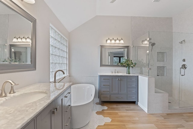 full bathroom featuring a freestanding tub, a stall shower, vaulted ceiling, and a sink